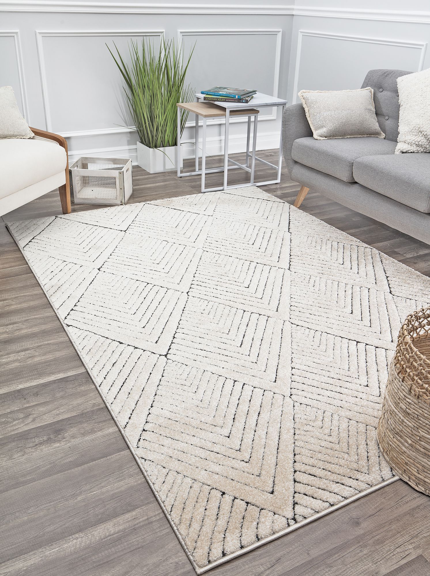 Geometric patterned area rug in light tones, placed on a wooden floor, with modern furniture including a gray sofa and a small white table.