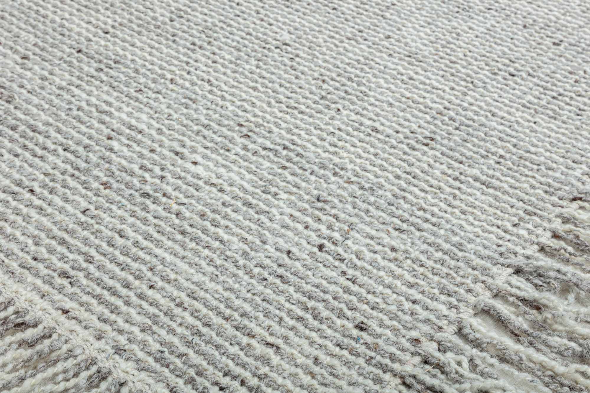 Close-up view of a textured beige and cream woven area rug, showcasing its intricate weave pattern and soft, natural fibers.
