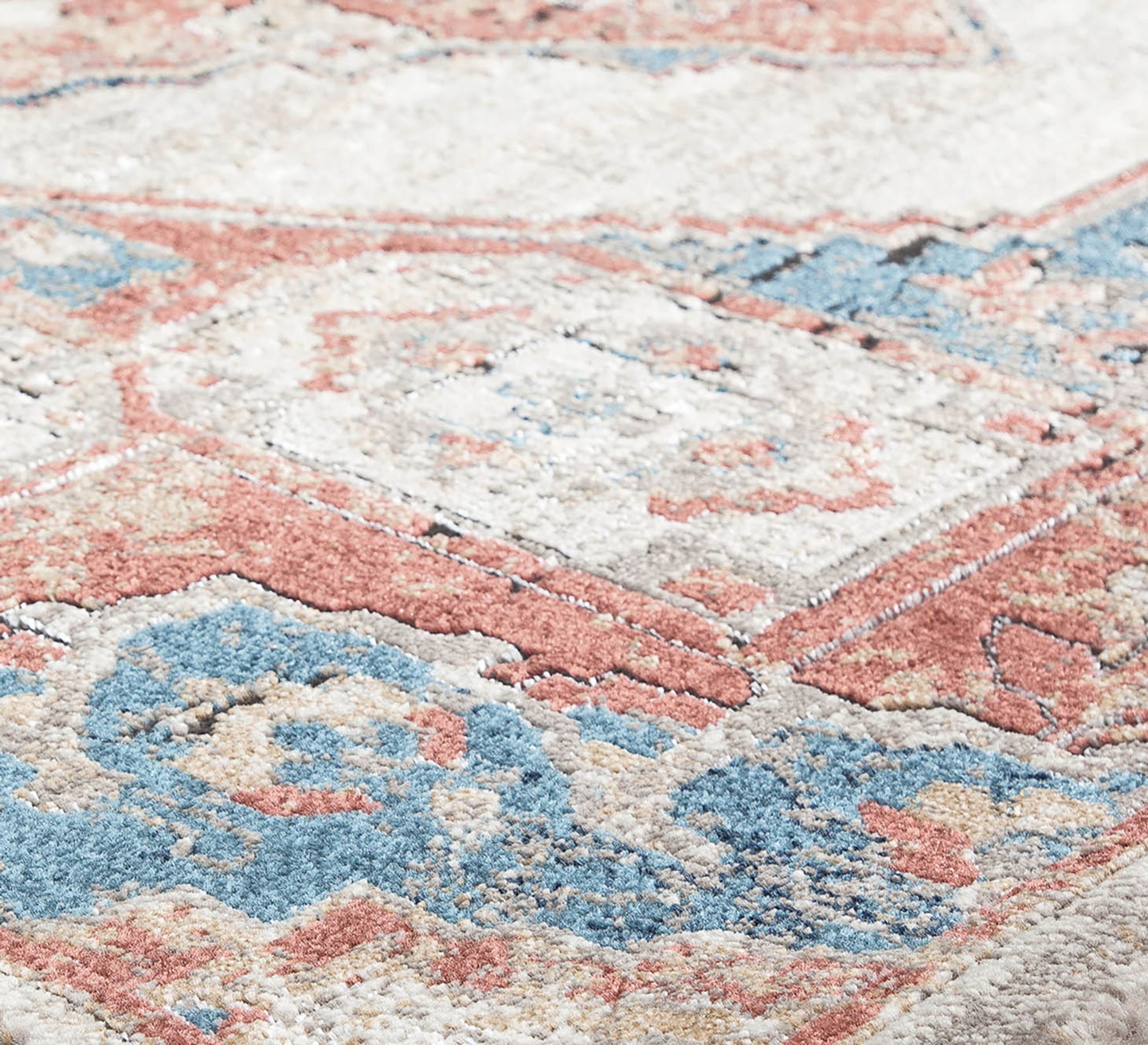 Close-up view of an area rug with a mixed harvest pattern, featuring intricate designs in shades of red, blue, and cream.